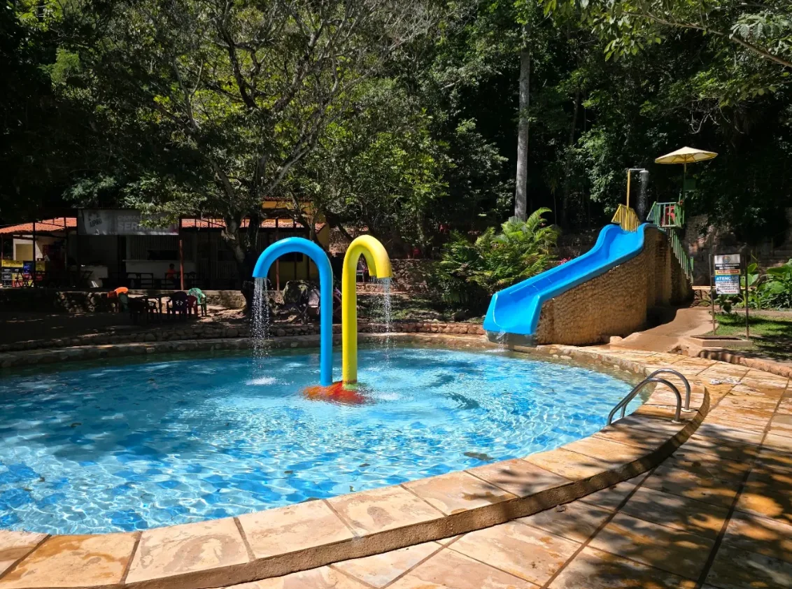 Piscina de água corrente com toboágua e arcos coloridos no Balneário do Caldas